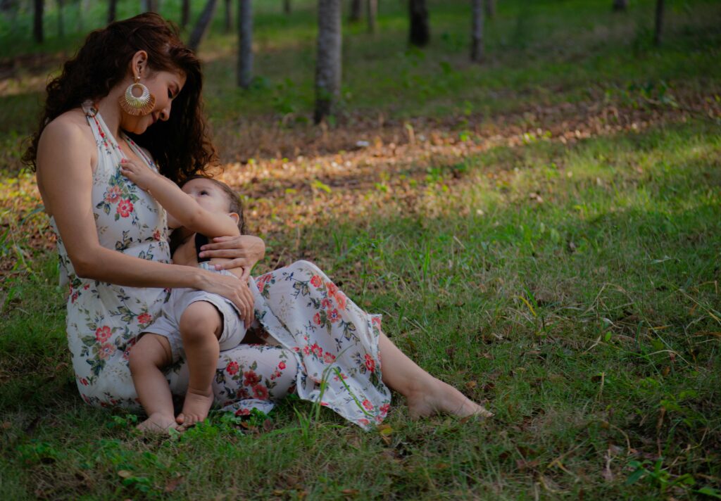 A mother lovingly breastfeeding her child in a peaceful outdoor setting.